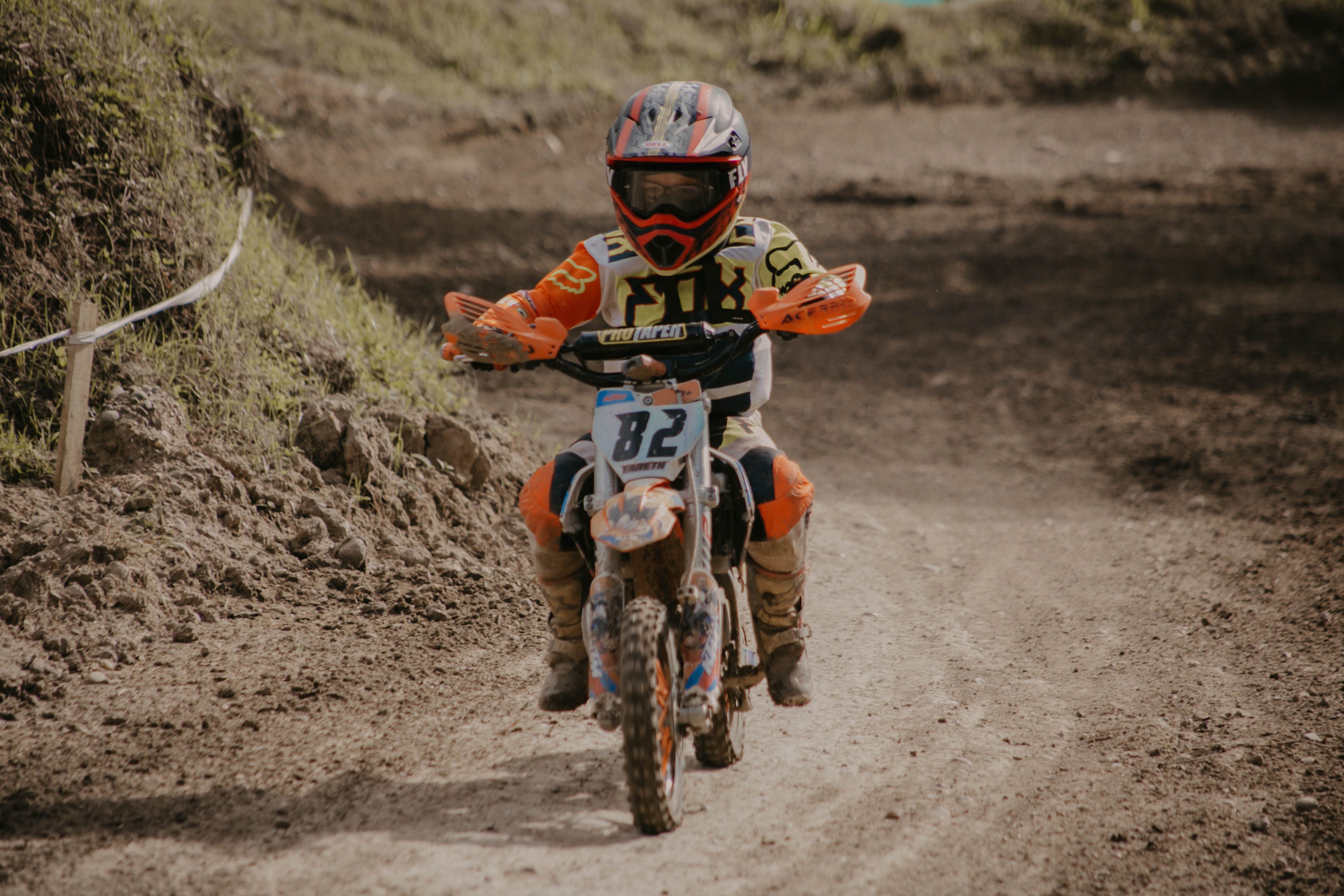 A young biker races on a dirt bike track, showcasing exciting motocross skills.