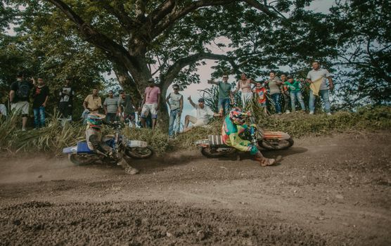 Exciting motocross race with two riders competing on a dirt track, surrounded by enthusiastic spectators.