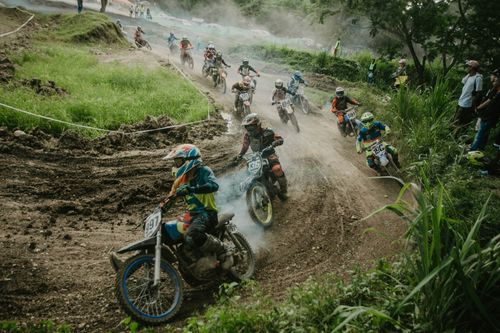 Free Dirt bike racers competing fiercely on a winding outdoor track amidst greenery. Stock Photo