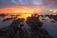 日落映照在岩石海岸上，活泼地捕捉到大自然的美丽