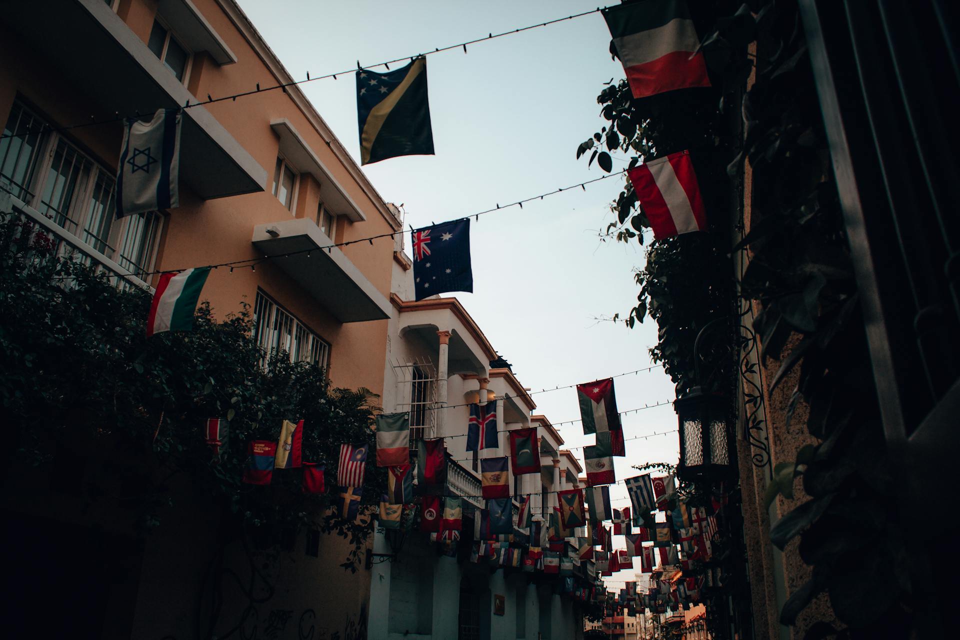 Vibrant alley in Cartagena adorned with hanging flags, showcasing a lively urban atmosphere.