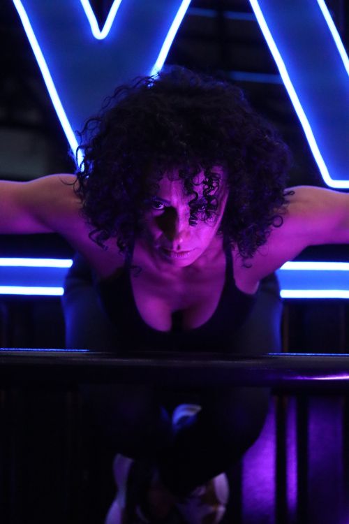 Free Woman focusing on intense workout under dramatic neon lights for fitness inspiration. Stock Photo