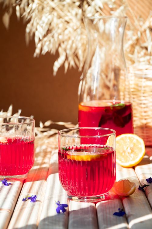 Free Enjoy the refreshing taste of pink lemonade with lemon slices on a sunlit table. Stock Photo