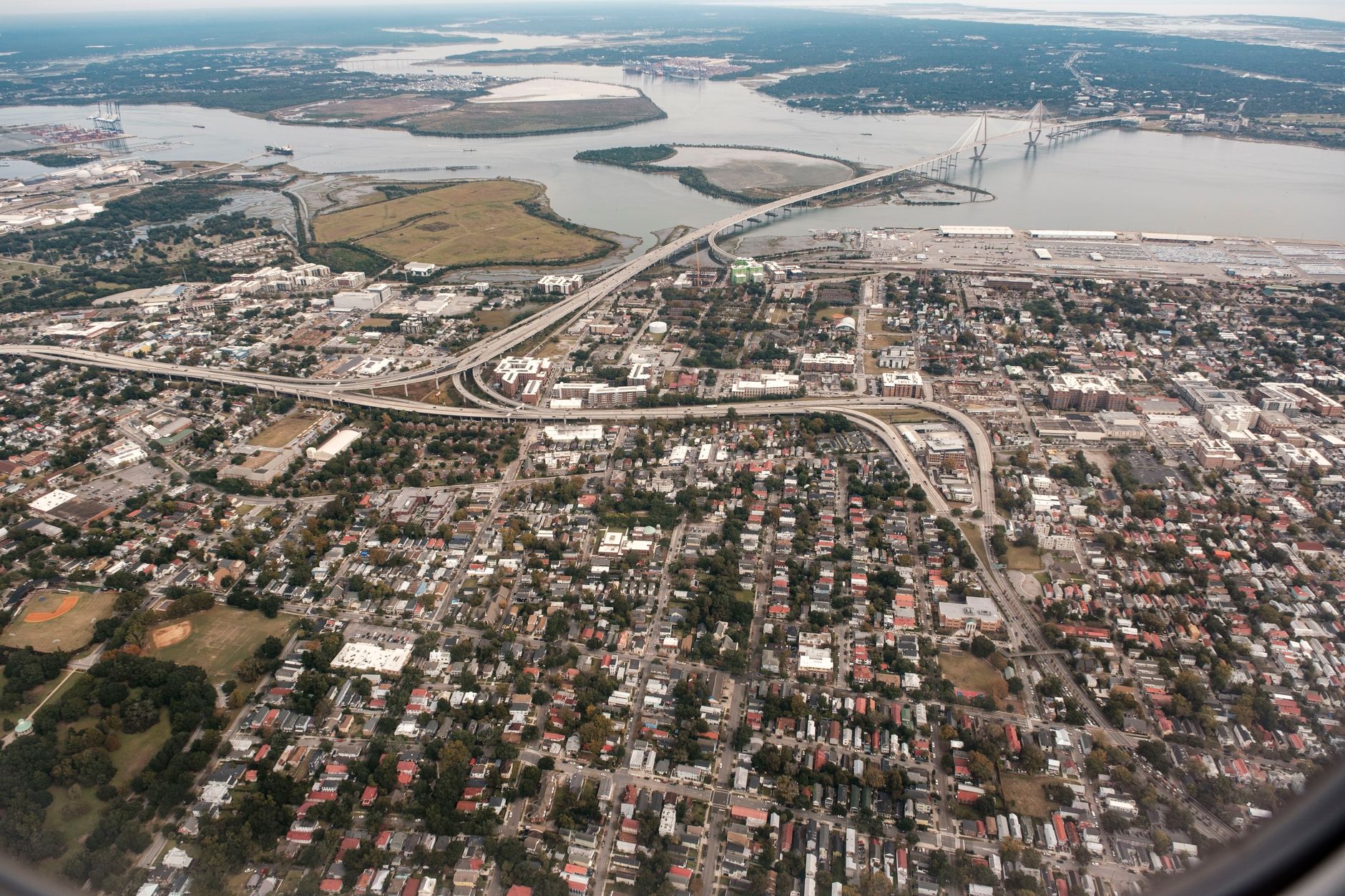 A stunning aerial photograph of Charleston, South Carolina, showcasing the city's layout and the iconic Arthur Ravenel Jr. Bridge.