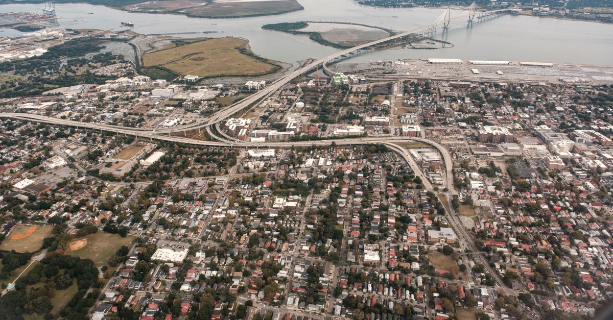 A stunning aerial photograph of Charleston, South Carolina, showcasing the city's layout and the iconic Arthur Ravenel Jr. Bridge.