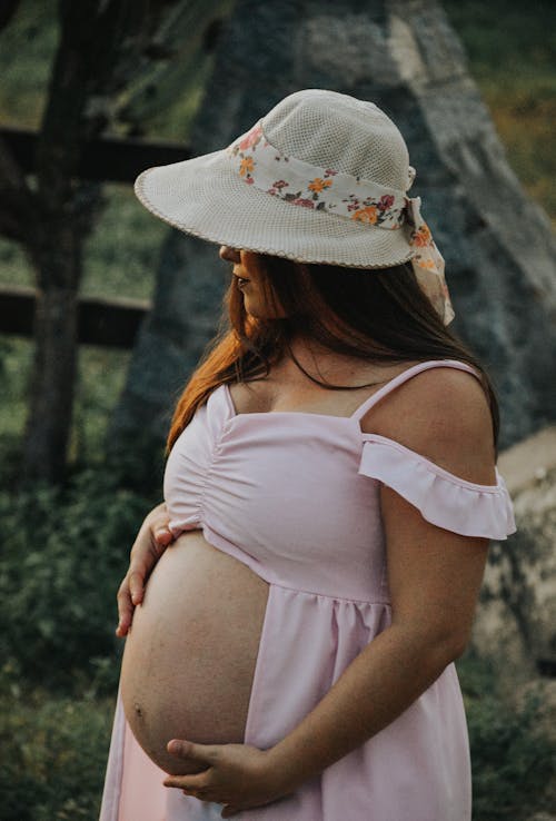 Pregnant Woman in White Floral Hat and White Dress
