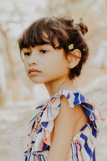 Serene portrait of a young girl in a colorful striped dress, outdoors in Aracati.