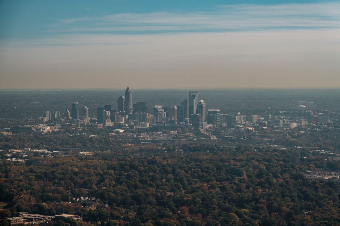 Aerial view of Charlotte area homes and skyline surrounded by fall foliage
