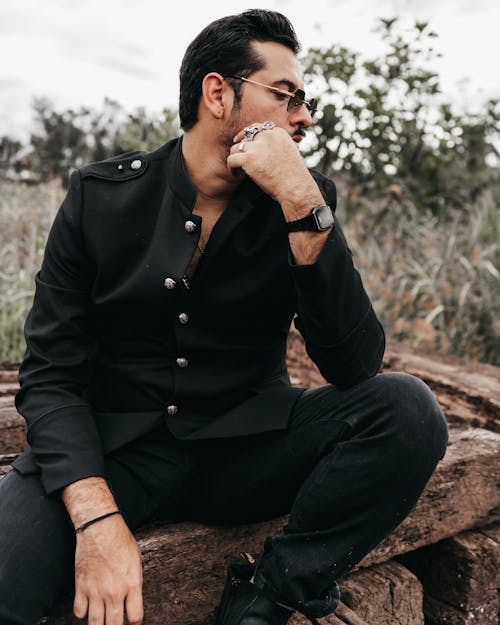 Man in Black Button Up Shirt Sitting on Brown Rock