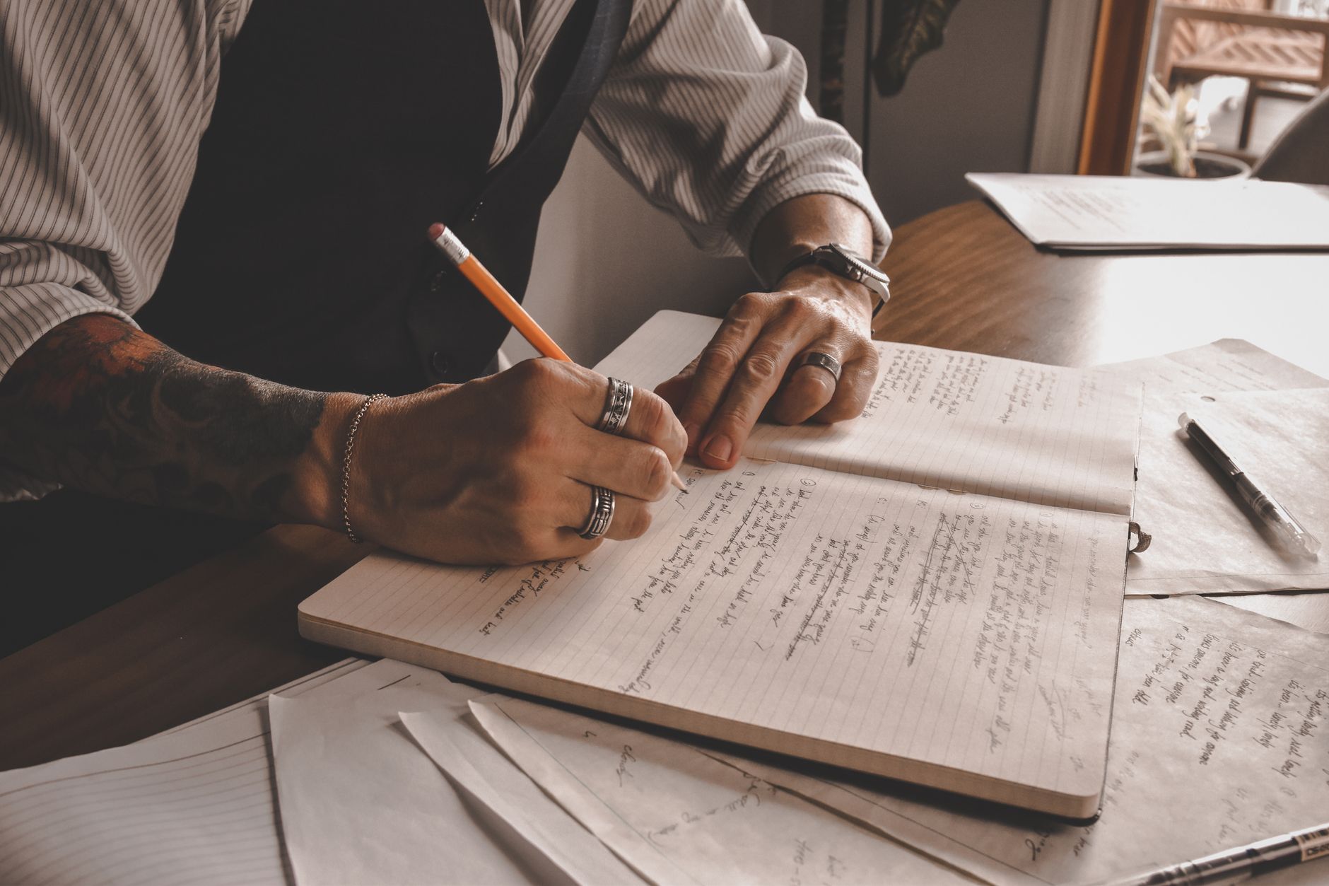 Close-up of a hand writing checklist notes in a notebook during planning.