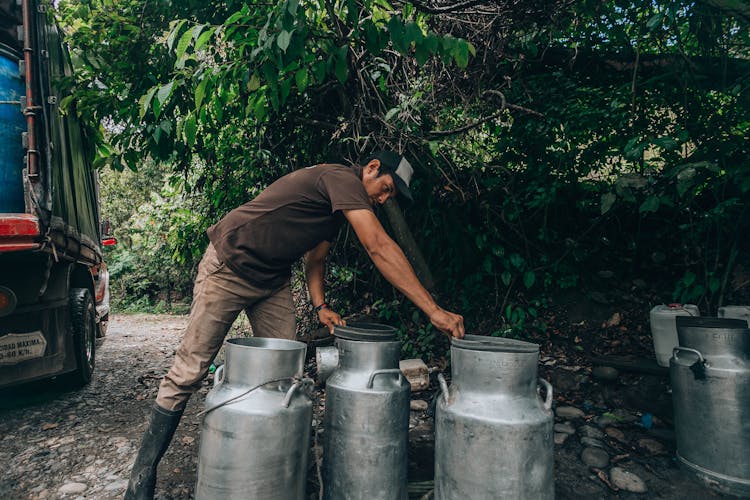 Man Loading Milk Buckets Into Truck