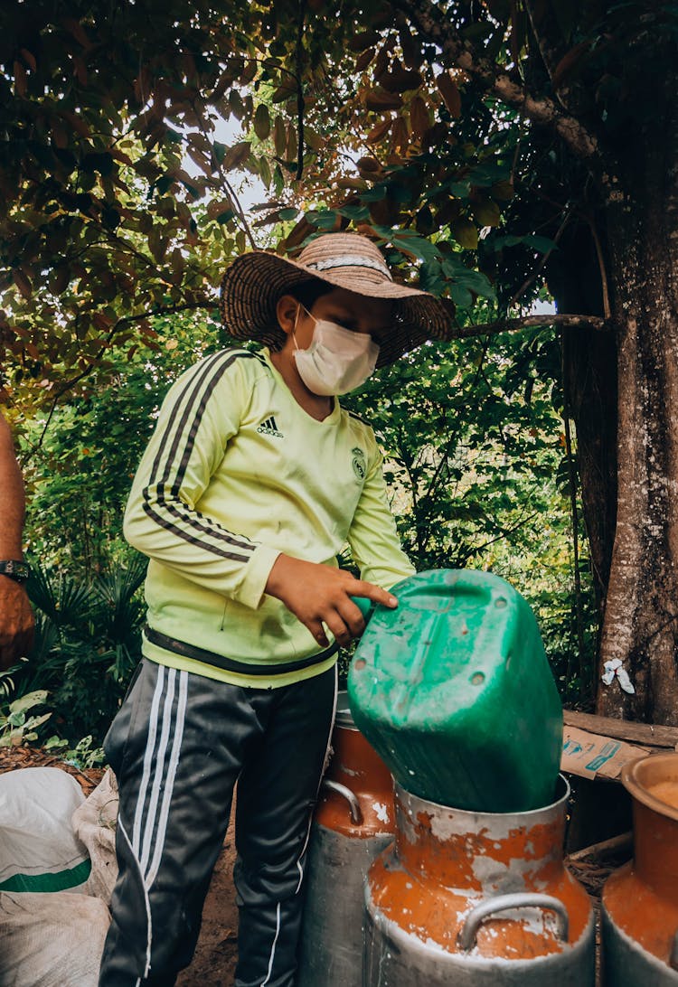 Person In Hat And With Mask Pouring From Bucket To Keg