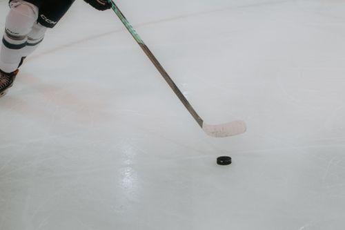 Free Focused hockey player handling the puck on the ice rink during a game. Stock Photo