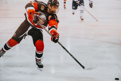 Free A male ice hockey player in full gear skates aggressively on ice during a game. Stock Photo