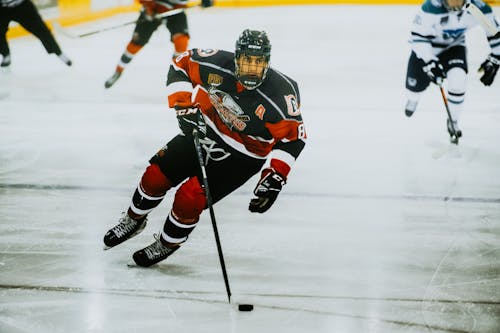 Free Man in Black and Red Ice Hockey Jersey Playing Hockey Stock Photo