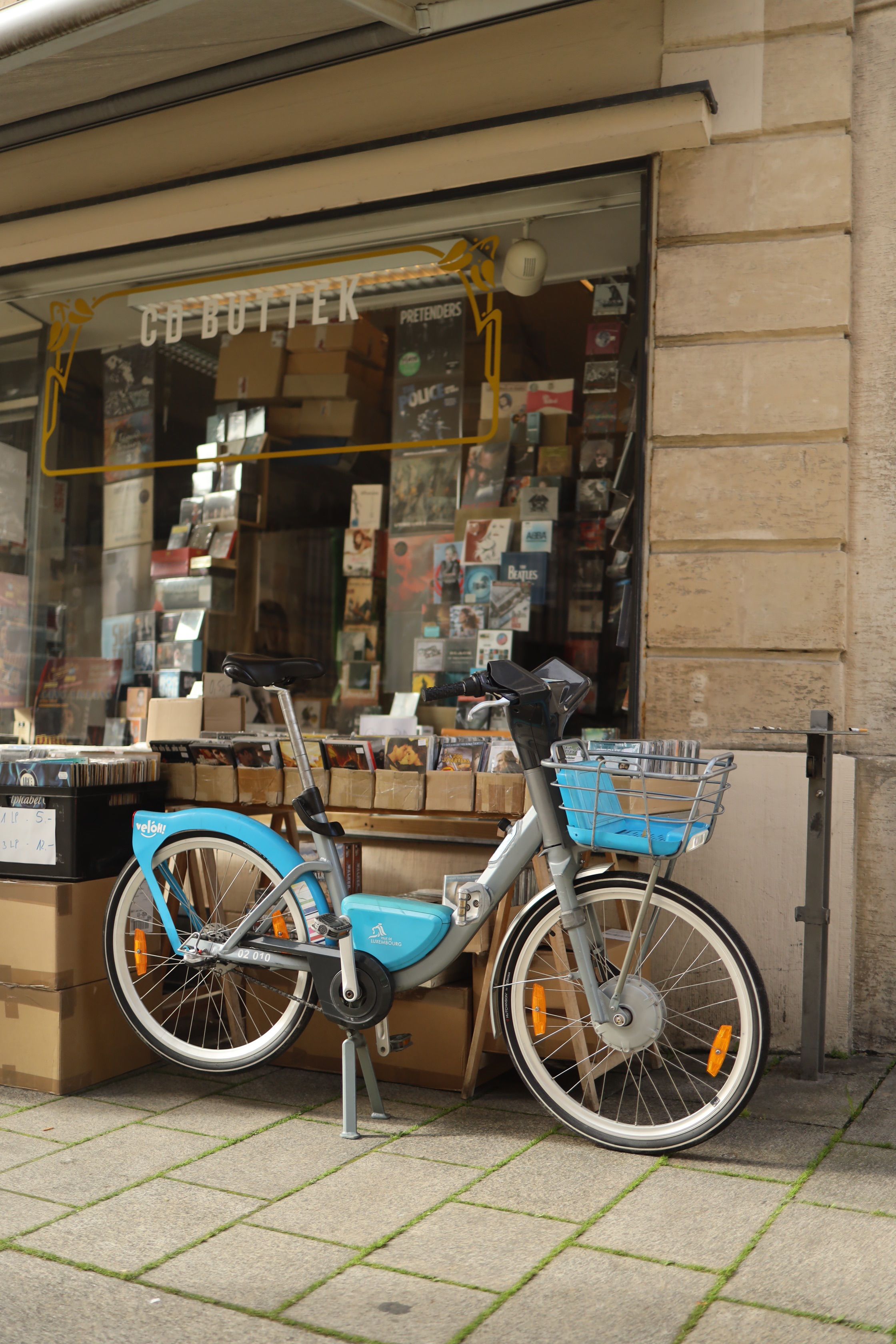 Bicycle parked outside a vintage CD shop in the city, showcasing urban lifestyle.