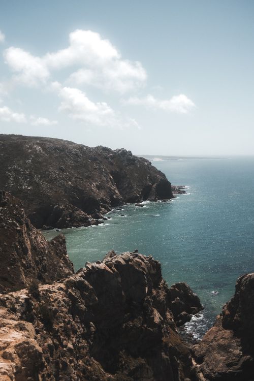Free Majestic rocky cliffs meet the azure Atlantic Ocean under a bright sky at Cabo da Roca, Portugal. Stock Photo