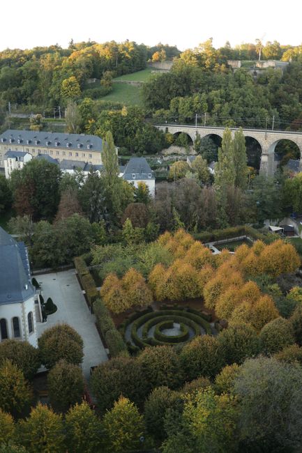 A scenic aerial view of lush green gardens and classical European architecture.
