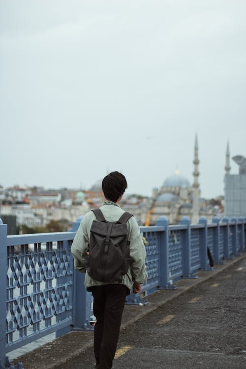A Man with a Backpack Walking on a Bridge