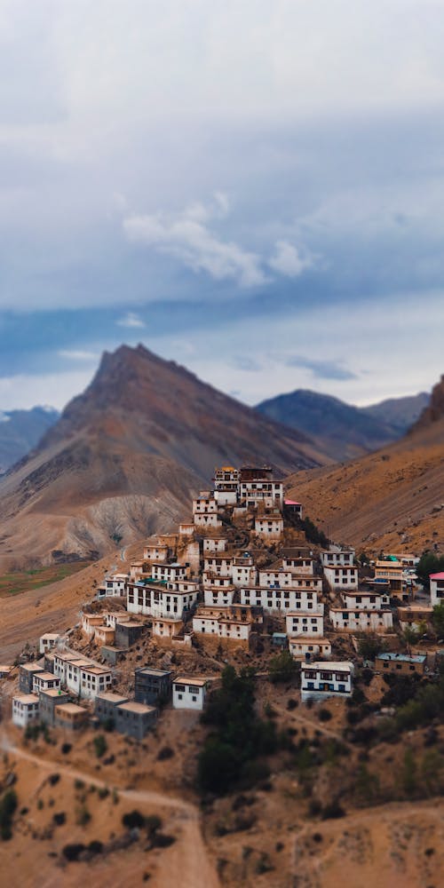 White and Brown Concrete Buildings Near Brown Mountain Under White Clouds and Blue Sky