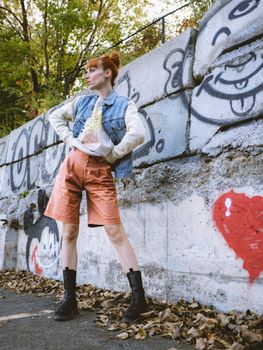 Fashionable woman posing against graffiti wall in Montreal during fall.