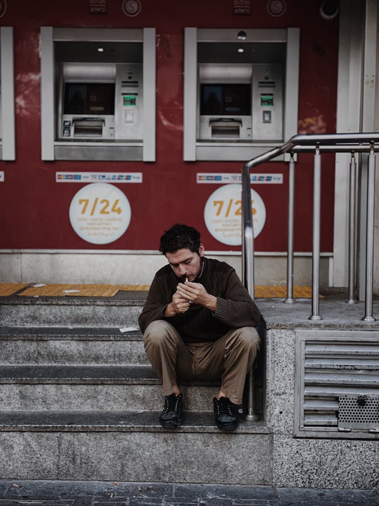 A Man Lighting A Cigarette Near ATM Machines