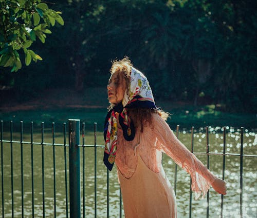 Photo of a Woman with a Headscarf Posing behind a Fence