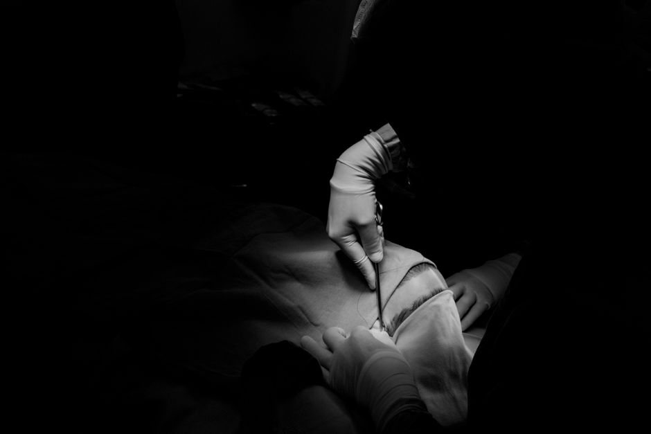 Dramatic black and white image capturing a surgical procedure, focusing on precision and care.