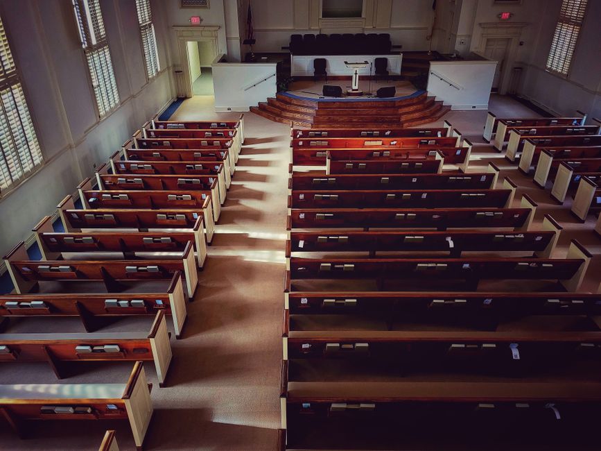 Sunlit interior of a peaceful church with neatly arranged wooden pews and an altar