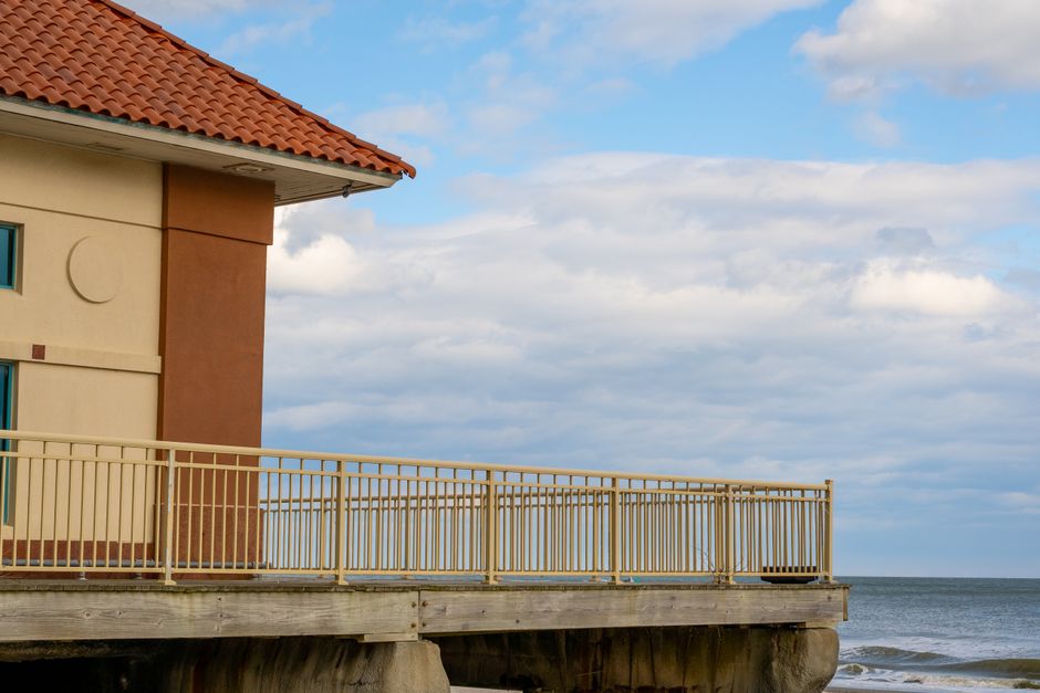 A scenic view from a seaside balcony overlooking the ocean under a partly cloudy sky.