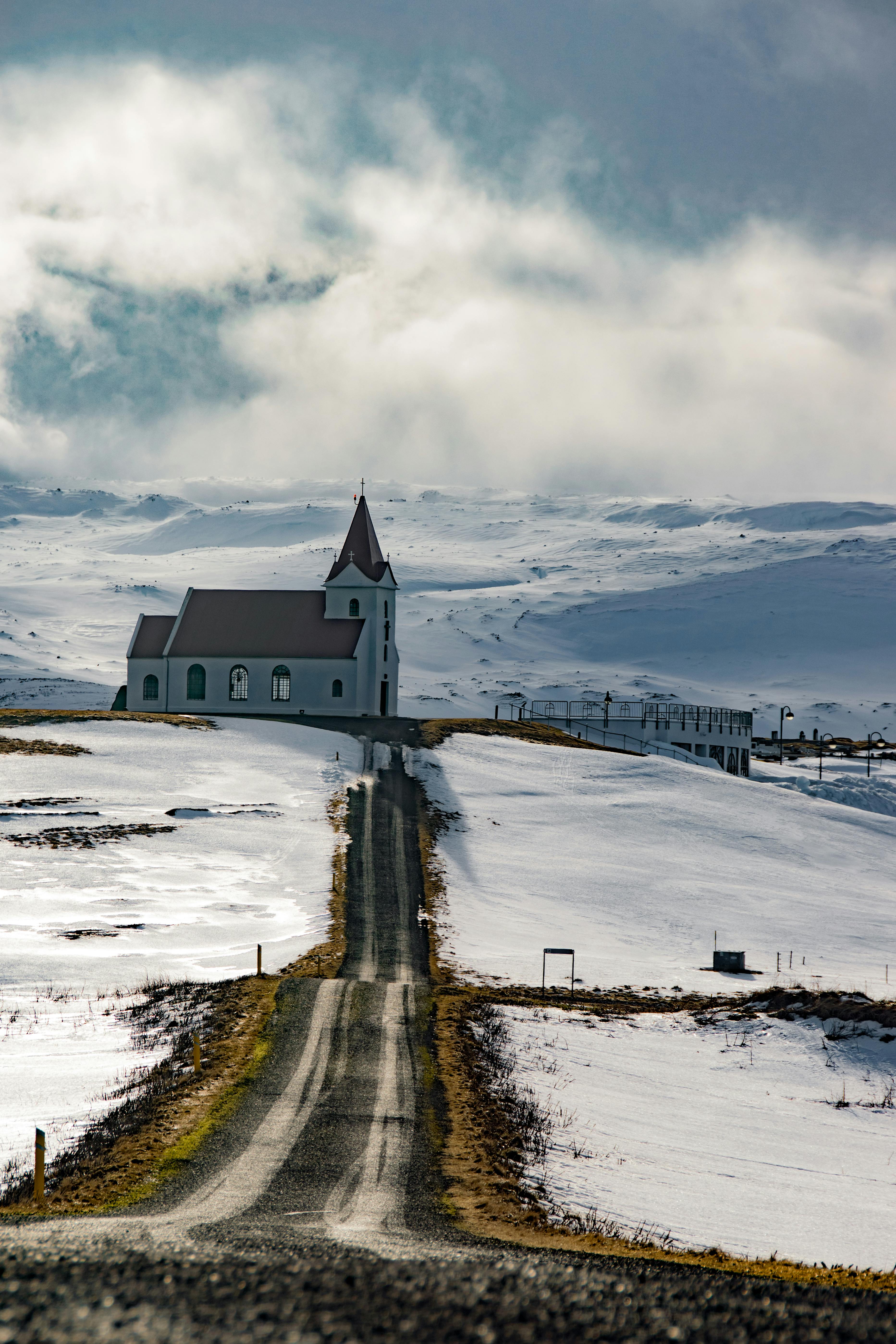 冰岛白雪皑皑的风景中，一座孤立的教堂矗立在多云的天空下