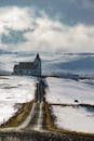 冰岛白雪皑皑的风景中，一座孤立的教堂矗立在多云的天空下
