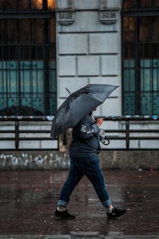 A woman with an umbrella walks past a building on a rainy day.