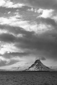 这是一张引人注目的黑白照片，画面中是一座白雪皑皑的山脉，天空如海洋般广阔