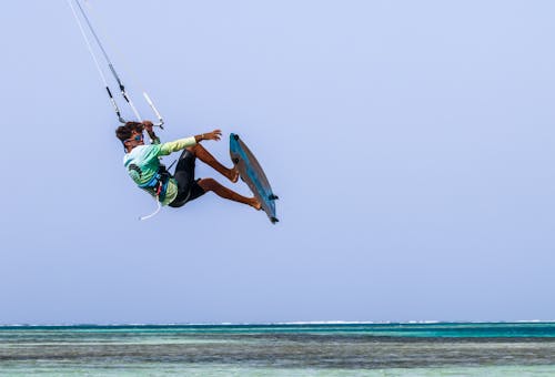 A Man in Green Shirt and Black Shorts Doing Surfing