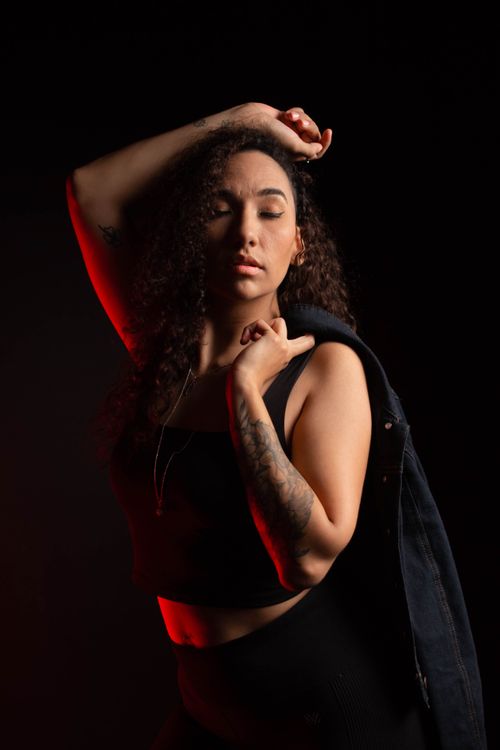 Free Stylized portrait of a woman in red lighting, eyes closed, wearing a jacket. Stock Photo