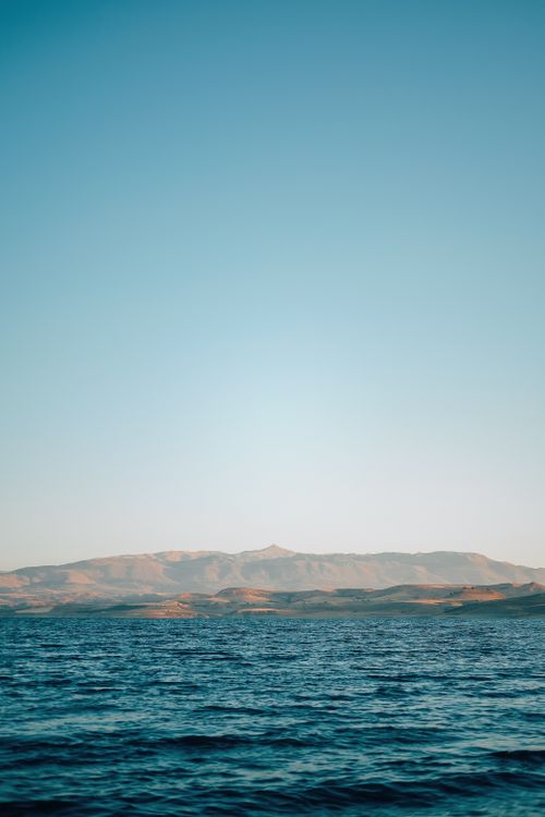 Free Peaceful view of ocean and gentle mountain in Adıyaman, Turkey under a clear blue sky. Stock Photo
