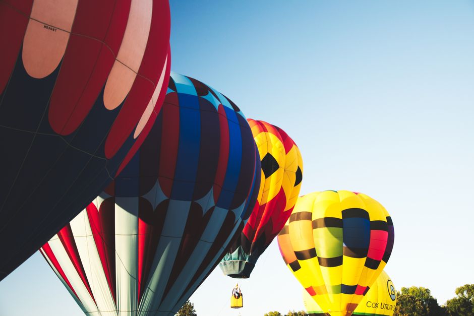 Colorful hot air balloons ascend gracefully into a clear summer sky, capturing a sense of wanderlust and adventure.
