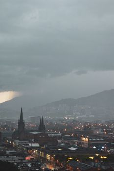 Aerial view of a cityscape with a foggy, moody atmosphere during dusk lighting.