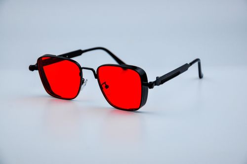 Free Close-up of red-tinted sunglasses with a modern design on a white background. Stock Photo