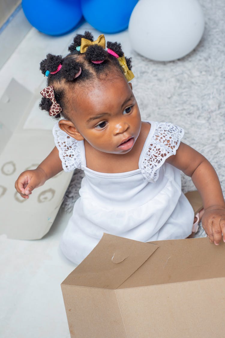 High-Angle Shot Of A Cute Baby Girl Wearing White Dress