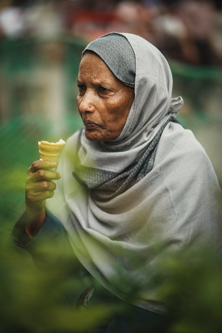 Old Woman In Hijab Eating Ice Cream Outdoors
