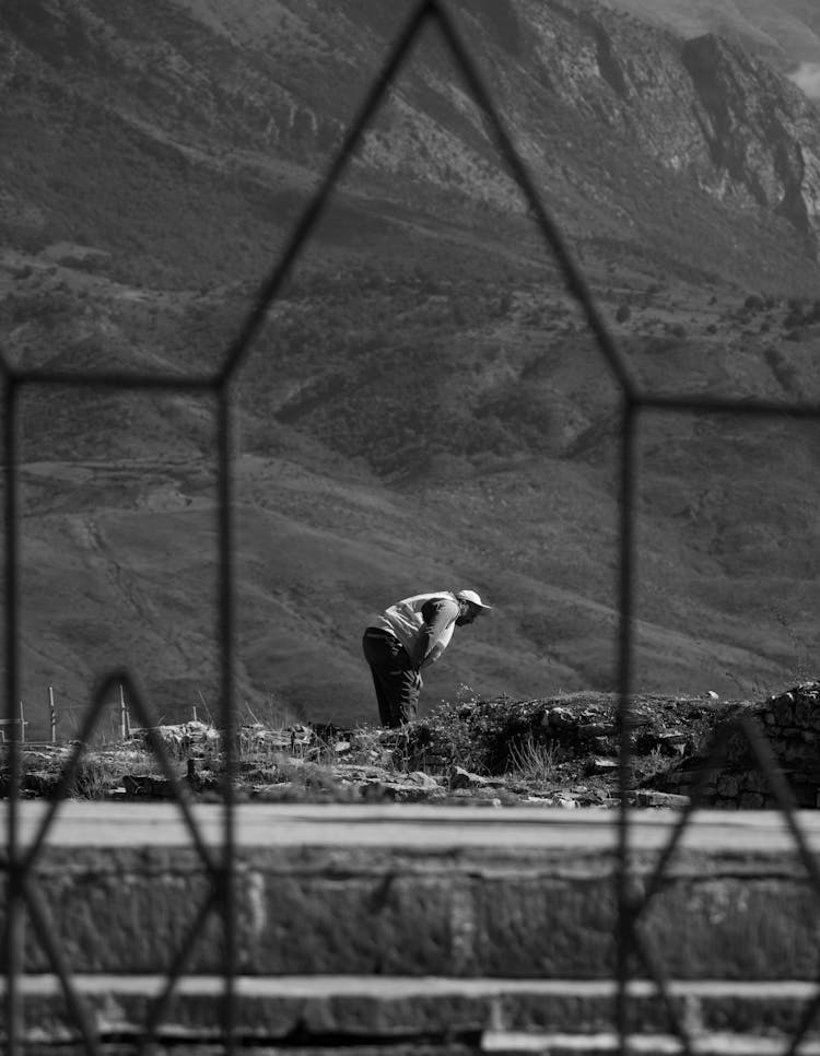 Man Bending Forward Near A Mountain