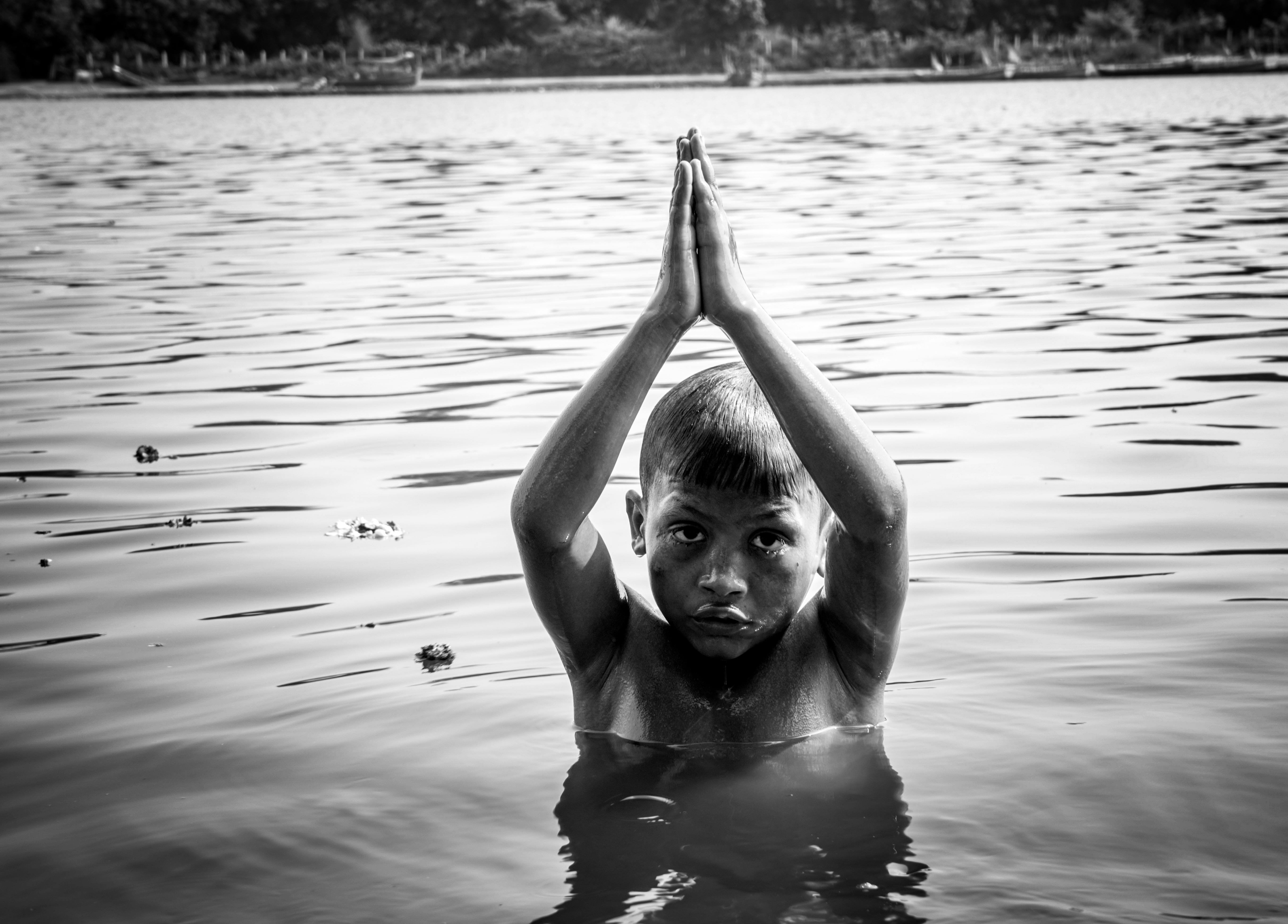 grayscale photo of a boy on the water