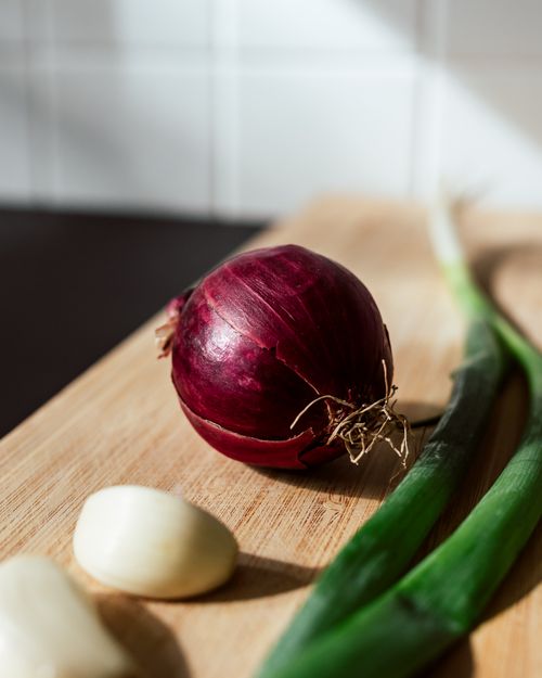 Free Close-up of fresh red onion, garlic, and green onion on a wooden board in the kitchen. Stock Photo