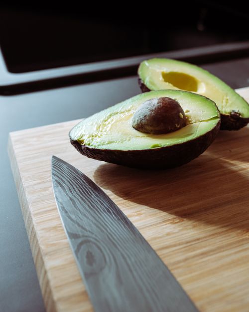 Free Fresh avocado sliced open on a wooden board with a knife in view, highlighting healthy eating. Stock Photo