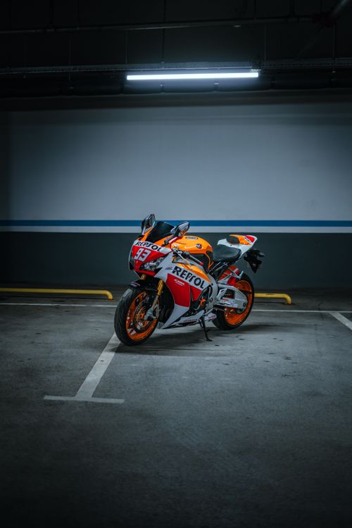 Free High-performance sports motorcycle parked in a dimly lit parking lot, emphasizing modern design and speed. Stock Photo