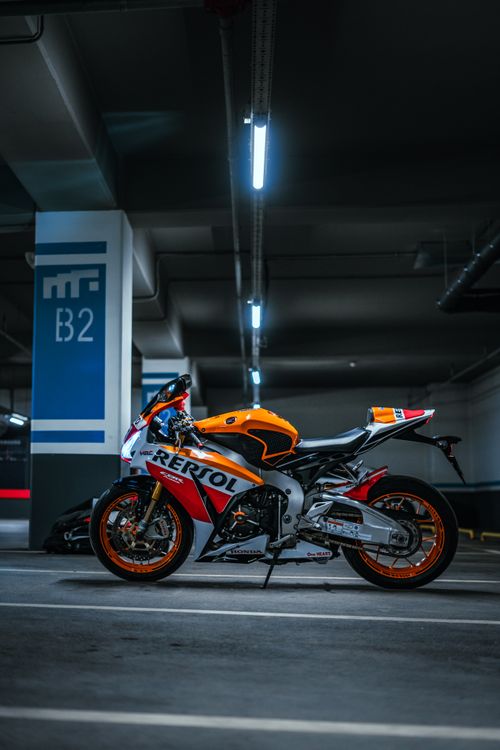 Free Orange and white sports motorcycle parked in an underground garage. Stock Photo