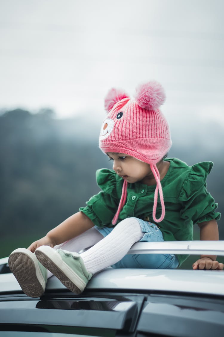 A Baby Girl Sitting On The Car Roof