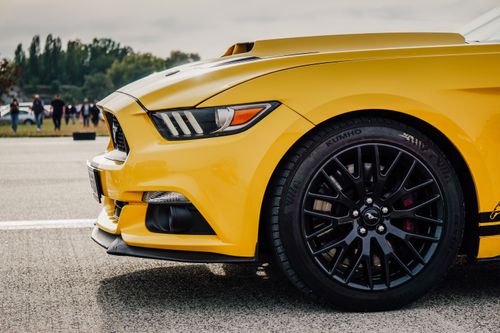 Free Dynamic close-up of a sleek yellow sports car on a sunny day, showcasing stylish design and performance tires. Stock Photo